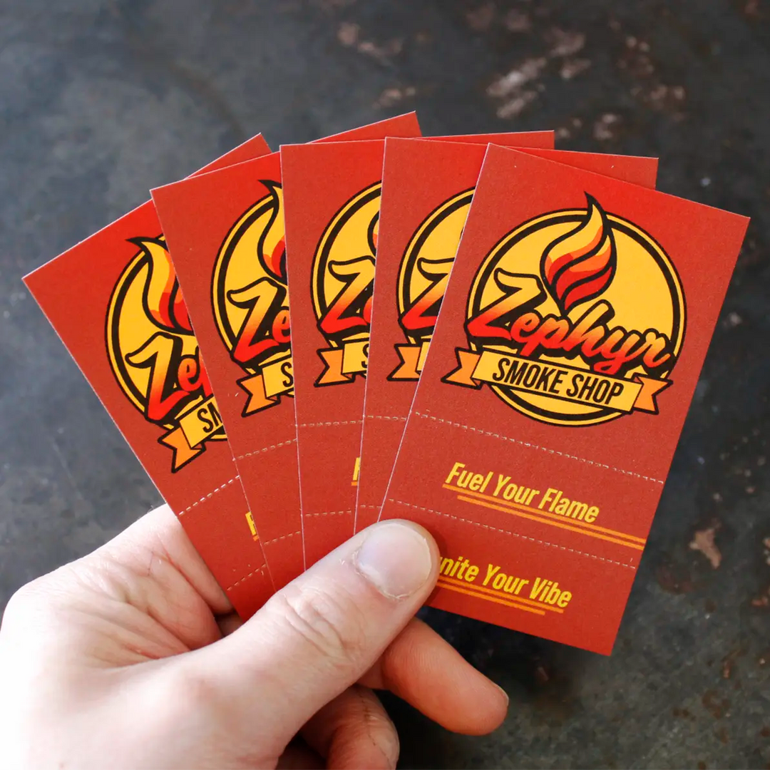 Hand holding a fanned-out set of five red Crutch Cards featuring the Zephyr Smoke Shop logo and slogan “Fuel Your Flame, Ignite Your Vibe,” with a dark textured background.
