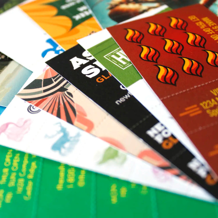 Close-up of Crutch Cards fanned out in a colorful, overlapping arrangement, showcasing a variety of custom designs and brand artwork printed on perforated hemp paper.