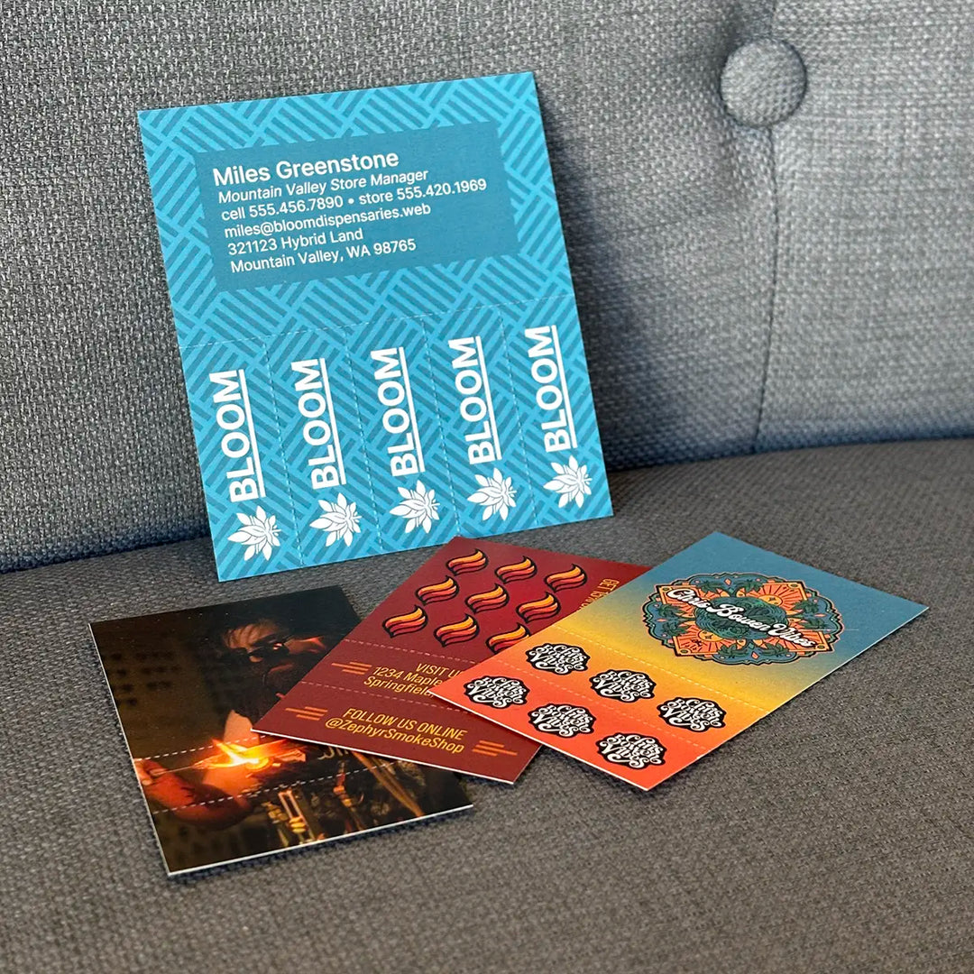 Collection of custom Crutch Cards arranged on a gray couch, including designs for Bloom Dispensaries, Zephyr Smoke Shop, and Chris Bowen Vibes.