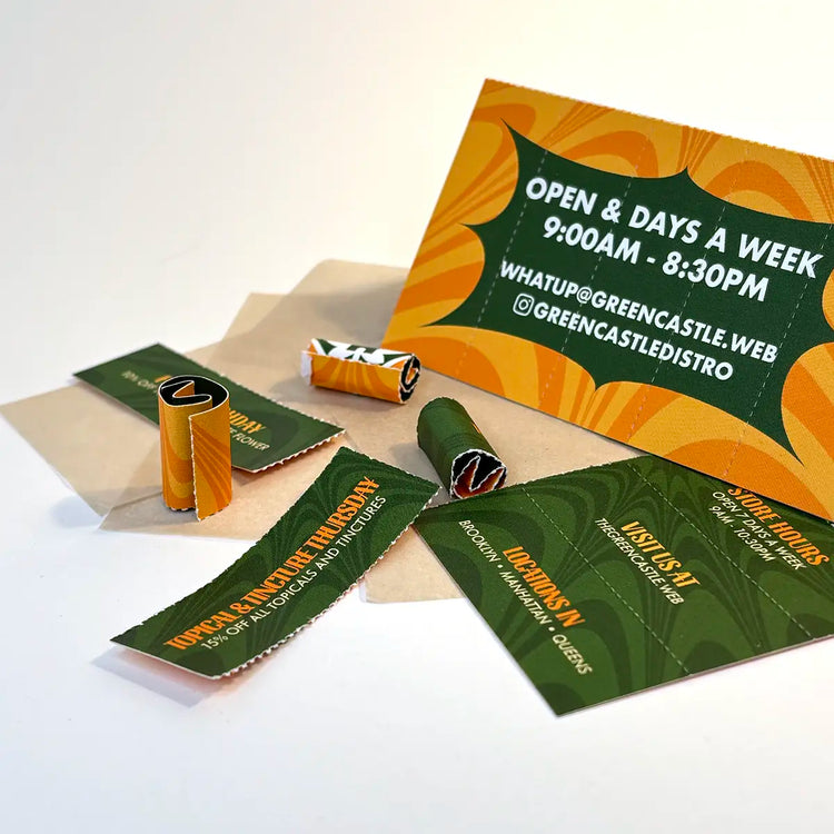 Crutch Cards for Green Castle laid out with rolled and unrolled tips on a white surface, featuring bold green and orange branding and store info.