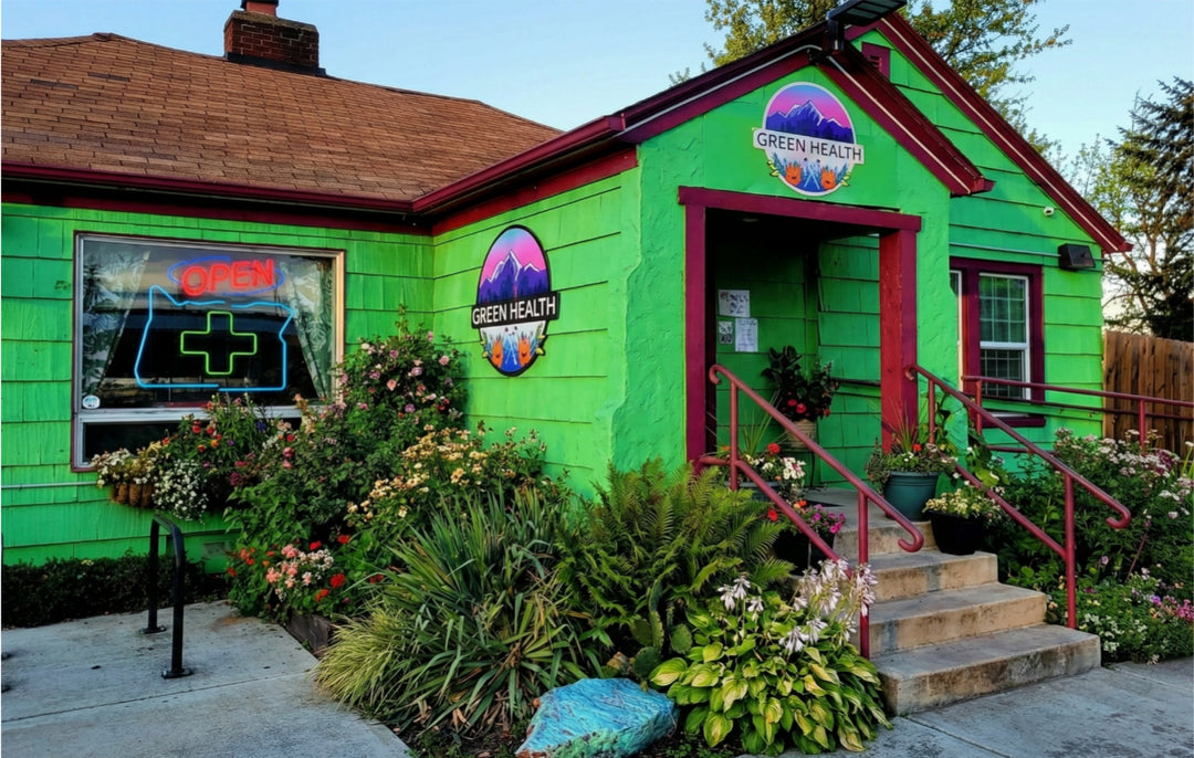 Green building with 'Green Health' sign, surrounded by plants and flowers.